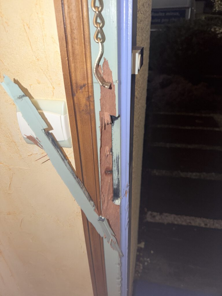 Montant de porte en bois éclaté et gâche arrachée après une effraction